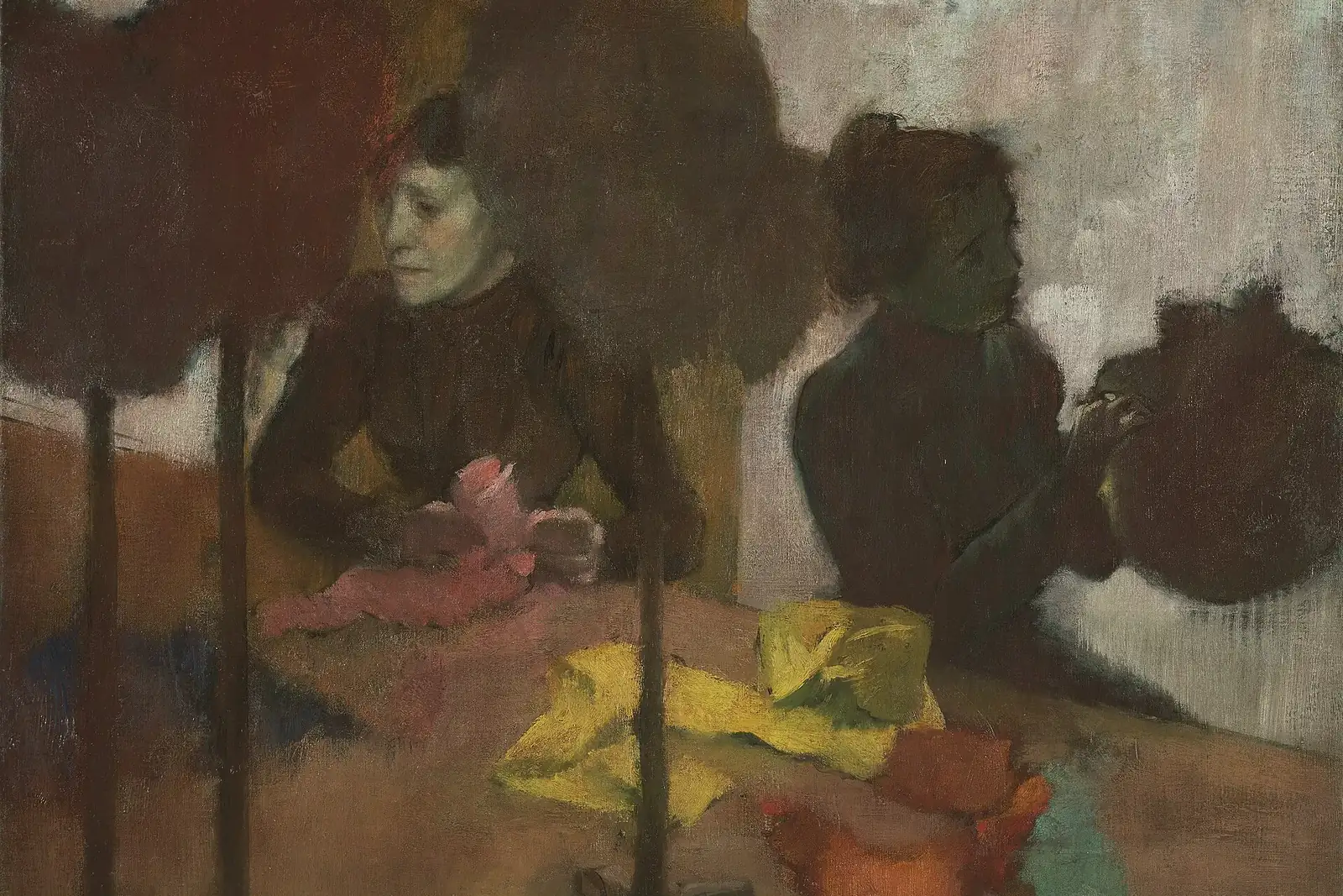 Peinture de deux modistes assises à une table couverte de rubans et de plumes jaunes, roses et rouges, entourées de chapeaux sur des porte-chapeaux